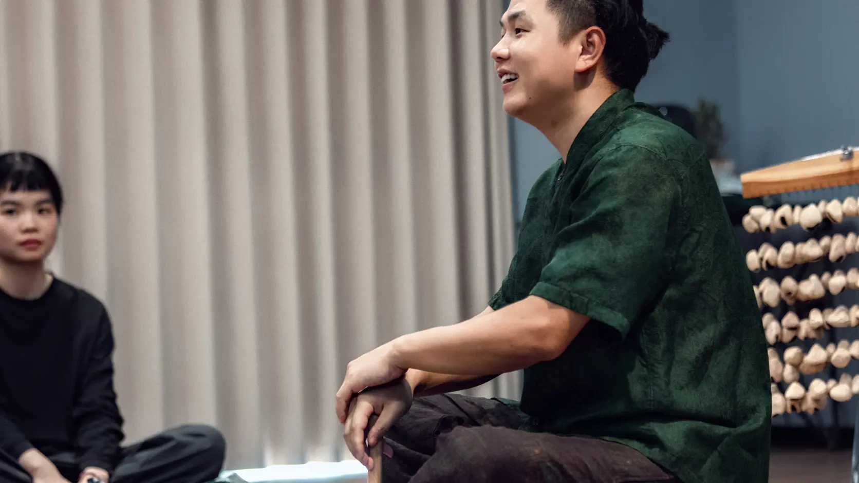 A facilitator speaks during a singing bowl learning activity while a participant listens